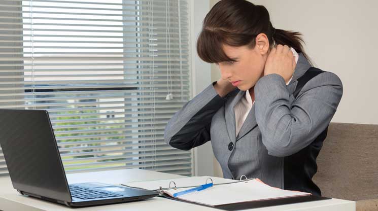 Woman stretching her neck sitting at office furniture